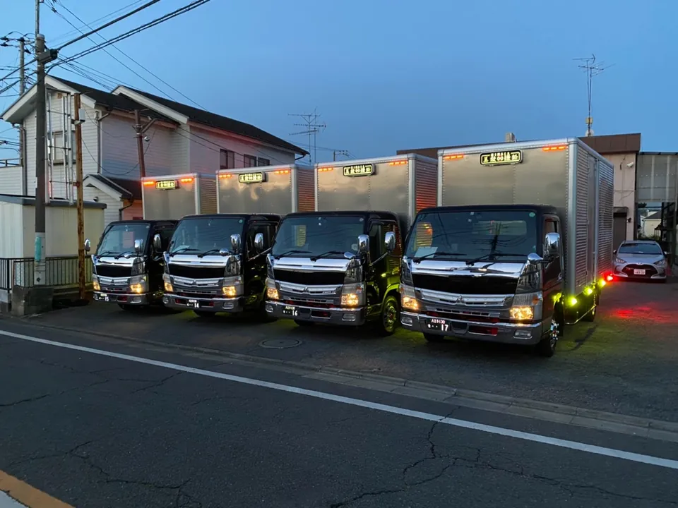 夕方の車庫でライトを点けて並ぶ2tトラック